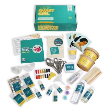 Fat lay of all materials included in kit in front of the Dear Smart Girl Cosmetic Scientist STEM Kit box.